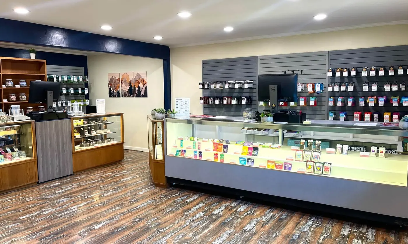 Inside Market St. Wellness: glass display cases, a wall of products, and mountain paintings under a navy beam